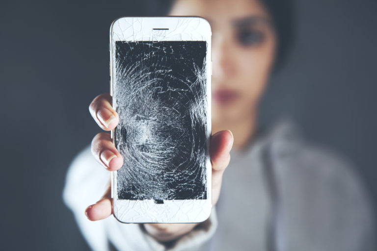woman holding a smartphone with a shattered screen