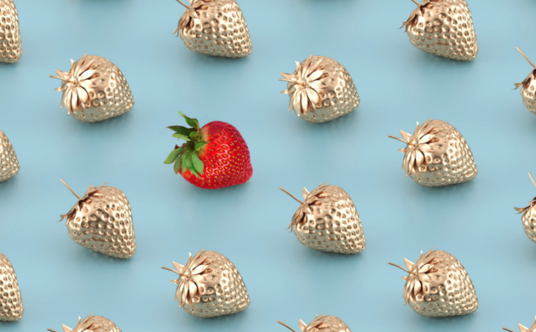 single red strawberry among multiple gold strawberries on a blue background